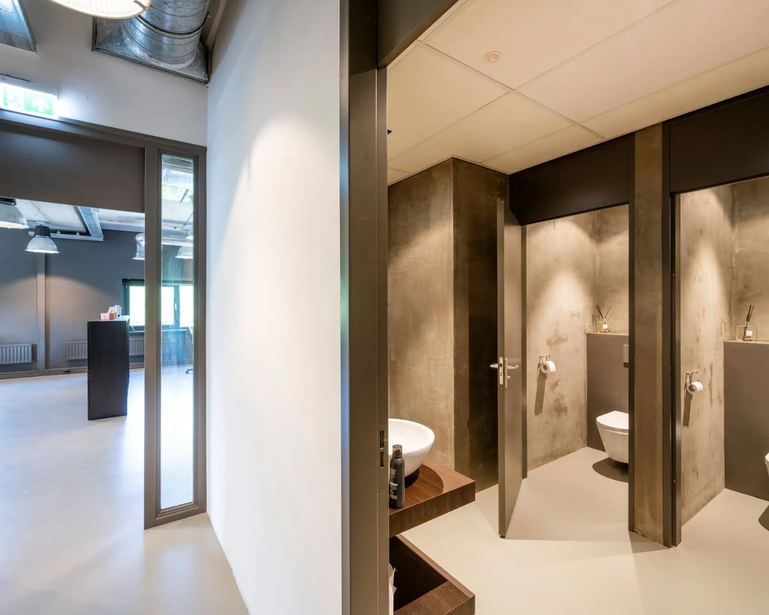 Moderne kantoorruimte aan de Overschiestraat 180 in Amsterdam met zicht op een industriële toiletruimte en een open werkruimte.