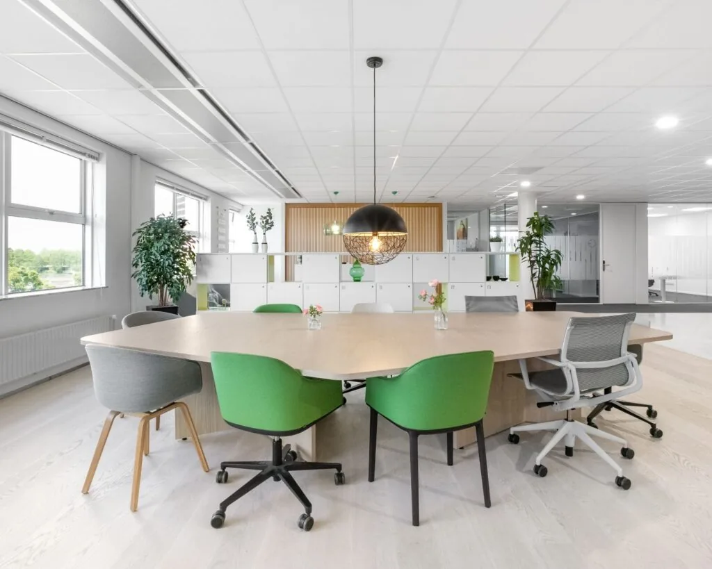 Moderne, lichte kantoorruimte in Pettelaarpark 84 in Den Bosch met vergadertafel, groene stoelen en grote ramen.