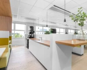 Moderne en lichte kantoorruimte in Pettelaarpark 84 in Den Bosch met een open keuken, zitgelegenheid en planten.