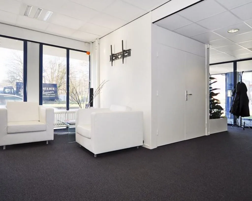 Moderne en lichte wachtruimte in een kantoor aan de Platinaweg 25 in Den Haag, met witte fauteuils en grote ramen.