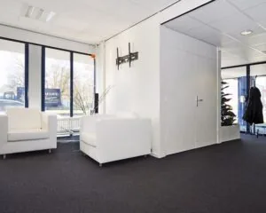 Moderne en lichte wachtruimte in een kantoor aan de Platinaweg 25 in Den Haag, met witte fauteuils en grote ramen.