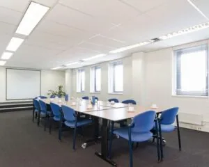 Vergaderruimte met blauwe stoelen en een groot projectiescherm in een kantoor aan de Platinaweg 25 in Den Haag.