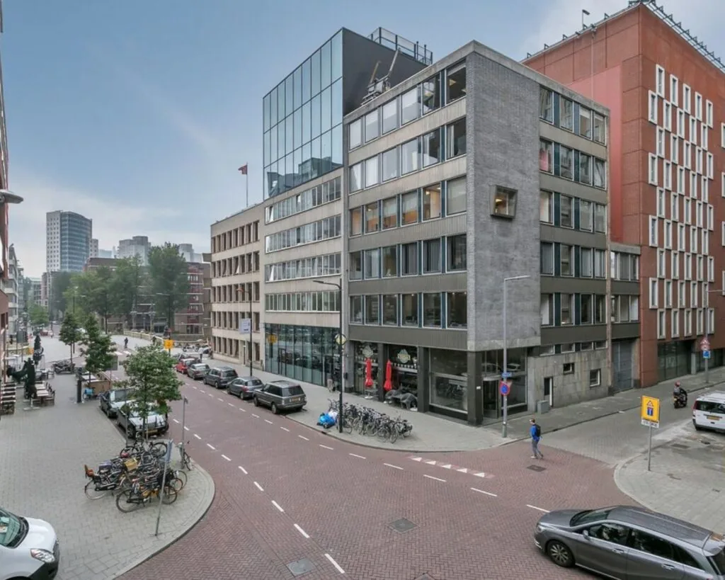 Straatbeeld met kantoorpand aan de Posthoornstraat 17 in Rotterdam, omringd door geparkeerde fietsen en auto's.