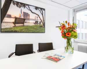 Moderne vergaderruimte aan de Posthoornstraat 17 in Rotterdam met bloemen op tafel en een foto van de Erasmusbrug aan de muur.