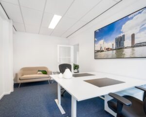 Moderne kantoorruimte aan de Posthoornstraat 17 in Rotterdam met bureaus, zithoek en een grote foto van de Rotterdamse skyline aan de muur.