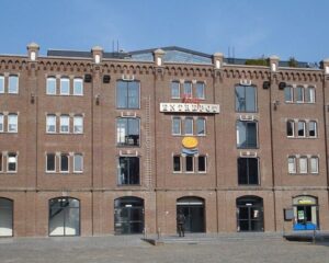 Bakstenen kantoorgebouw aan de Entrepothaven in Rotterdam met de naam 'ENTREPOT' op de gevel.