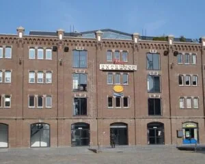 Bakstenen kantoorgebouw aan de Entrepothaven in Rotterdam met de naam 'ENTREPOT' op de gevel.