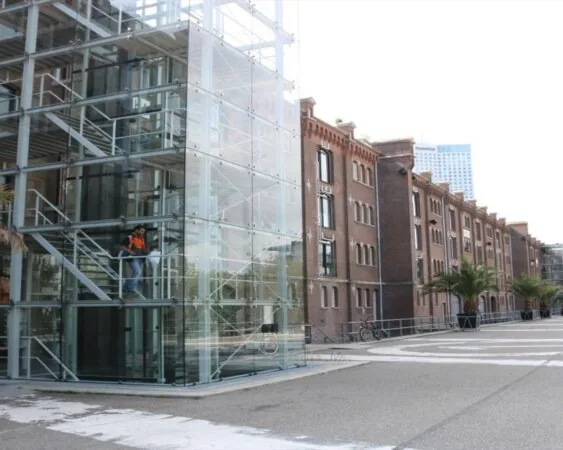 Moderne glazen entree met trappenhuis naast een historisch kantoorpand aan de Entrepothaven in Rotterdam.