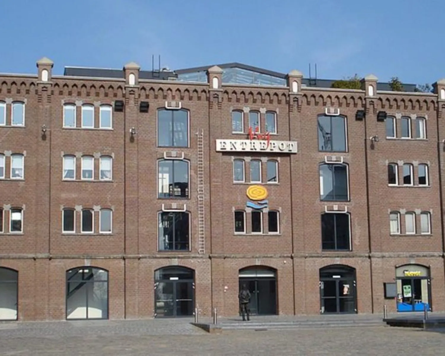 Bakstenen kantoorgebouw aan de Entrepothaven in Rotterdam met de naam 'ENTREPOT' op de gevel.