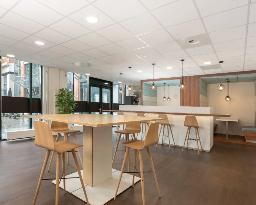 Moderne kantoorruimte aan het Stationsplein 91-105 in Den Bosch met hoge tafels, houten barkrukken en zithoeken met hanglampen.