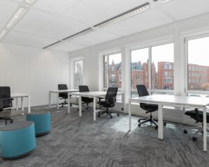 Moderne, lichte kantoorruimte met meerdere bureaus en uitzicht op het Stationsplein in Den Bosch.