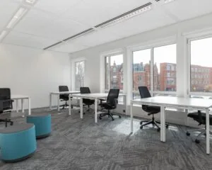 Moderne, lichte kantoorruimte met meerdere bureaus en uitzicht op het Stationsplein in Den Bosch.