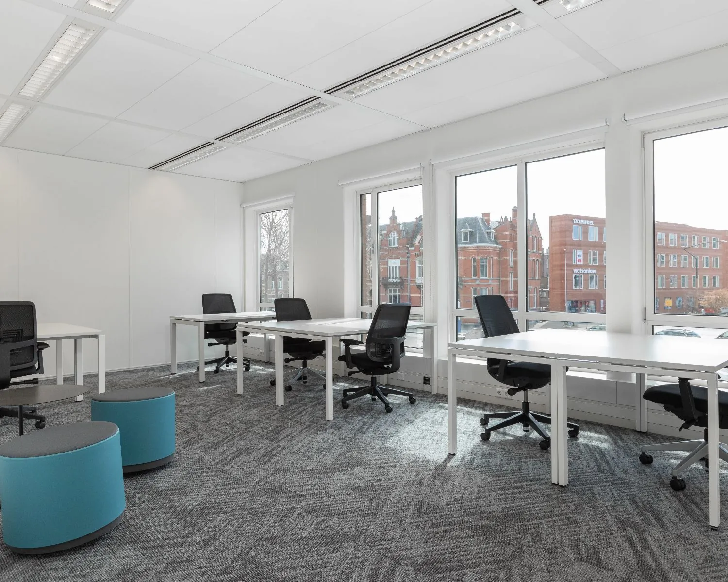 Moderne, lichte kantoorruimte met meerdere bureaus en uitzicht op het Stationsplein in Den Bosch.