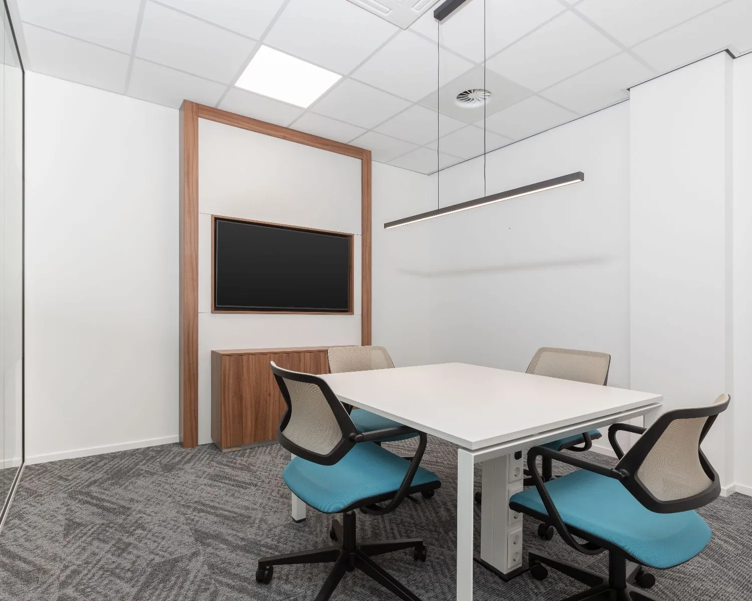 Moderne vergaderruimte met vier stoelen, een witte tafel en een flatscreen aan de muur in een kantoorpand aan het Stationsplein 91-105 in Den Bosch.