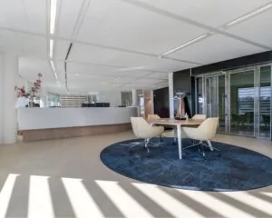 Moderne en lichte kantoorruimte aan het Stationsplein in Schiphol-Oost met een balie, vergadertafel en glazen deuren.