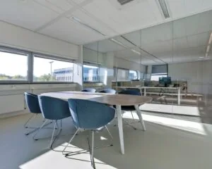 Moderne vergaderruimte met ovale houten tafel en blauwe stoelen in een kantoor aan het Stationsplein NO 438 in Schiphol-Oost.