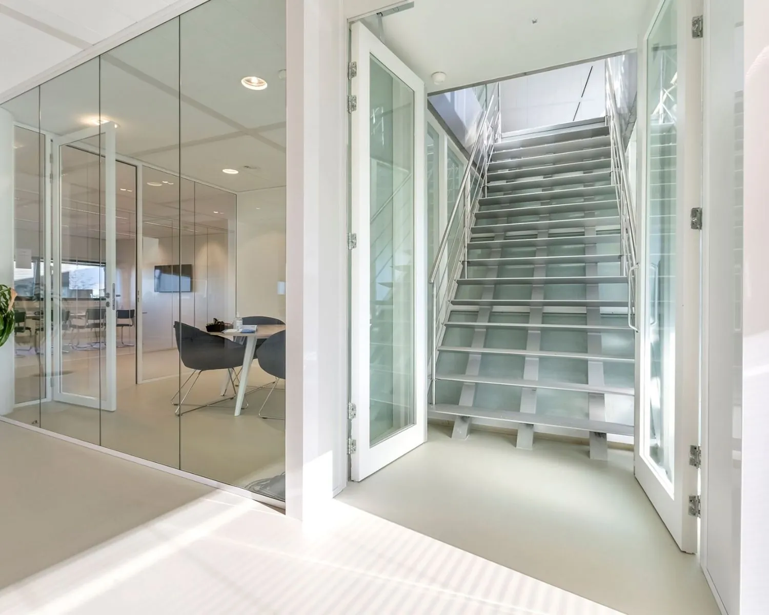 Moderne, lichte kantoorruimte met glazen wanden en een metalen trap in gebouw aan het Stationsplein in Schiphol-Oost.