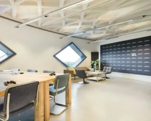 Moderne kantoorruimte in SugarCity met houten vergadertafel, loungehoek en diamantvormige ramen.