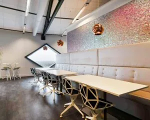 Moderne kantoorruimte in SugarCity Halfweg met designmeubilair, opvallende lampen en een grote diamantvormige raamopening.