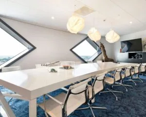 Moderne vergaderruimte in SugarCity Halfweg met lange witte tafel, designstoelen en grote ruitvormige ramen.