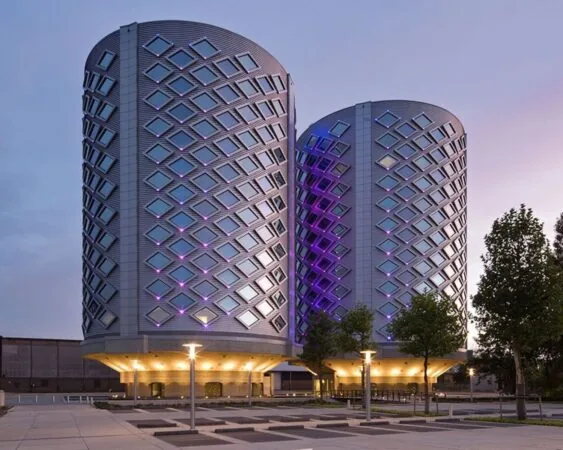 Twee futuristische kantoortorens van SugarCity aan de Ring in Halfweg, verlicht met paarse en blauwe accenten in de avondschemering.