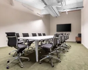 Moderne vergaderruimte met lange tafel, twaalf bureaustoelen en een flatscreen aan de muur in Velperplein 23, Arnhem.