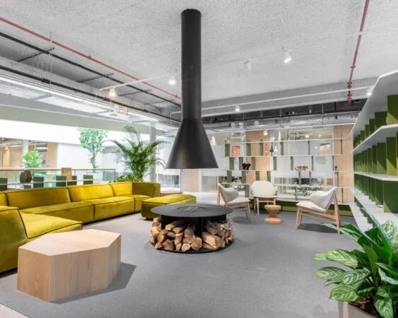 Moderne loungehoek in een kantoorruimte aan het Velperplein 23 in Arnhem met gele bank, open haard en groene accenten.