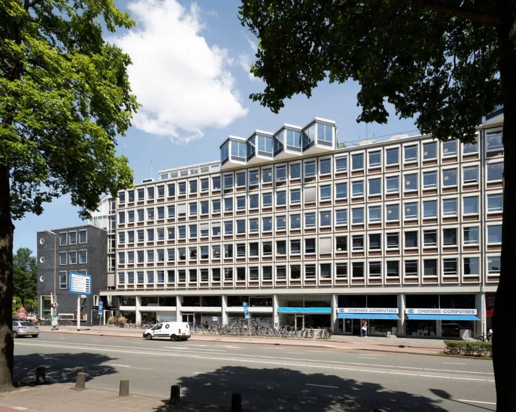 Vooraanzicht van een modern kantoorgebouw aan de Weesperstraat 61 in Amsterdam met veel ramen en fietsen geparkeerd voor de ingang.