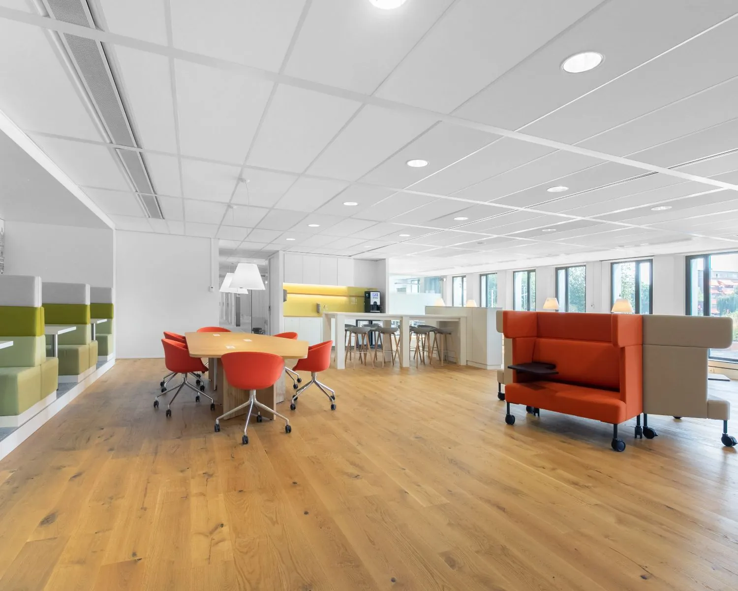 Moderne, lichte kantoorruimte op Willemsplein 2 in Den Bosch met houten vloer, oranje stoelen en open werkplekken.