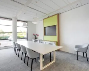 Moderne vergaderruimte in een kantoor aan de Databankweg 26 in Amersfoort met grote tafel, acht stoelen, flatscreen en veel daglicht.