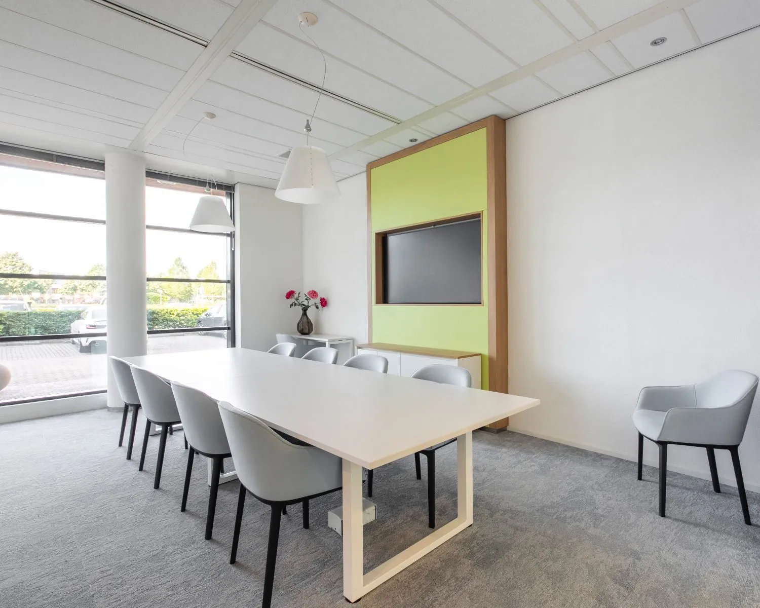 Moderne vergaderruimte in een kantoor aan de Databankweg 26 in Amersfoort met grote tafel, acht stoelen, flatscreen en veel daglicht.