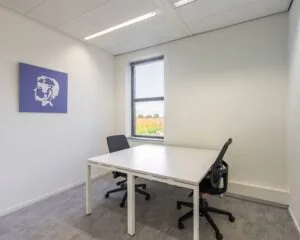 Kleine, lichte kantoorruimte met twee bureaustoelen, een raam en een kunstwerk aan de muur in Amersfoort aan de Databankweg 26.