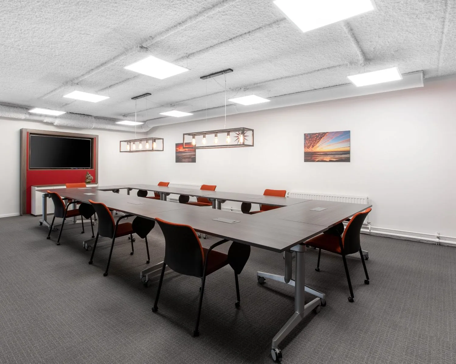 Moderne vergaderruimte met U-vormige opstelling, flatscreen en kunst aan de muur in een kantoor aan het Stationsplein 13A in Amersfoort.