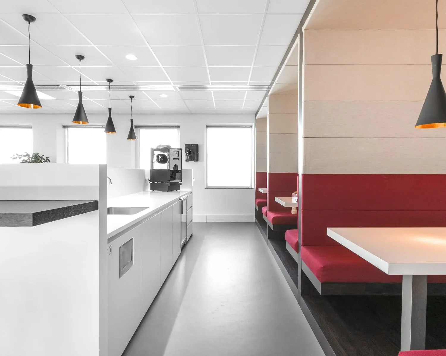 Moderne kantine met rood-witte zitnissen en een kitchenette in kantoorruimte Queenstower aan de Delflandlaan in Amsterdam.