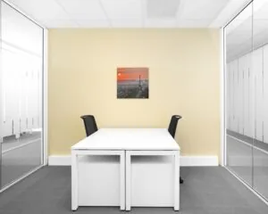 Moderne kantoorruimte in de Queenstower aan de Delflandlaan in Amsterdam met twee bureaus, glazen wanden en een foto van de Eiffeltoren aan de muur.