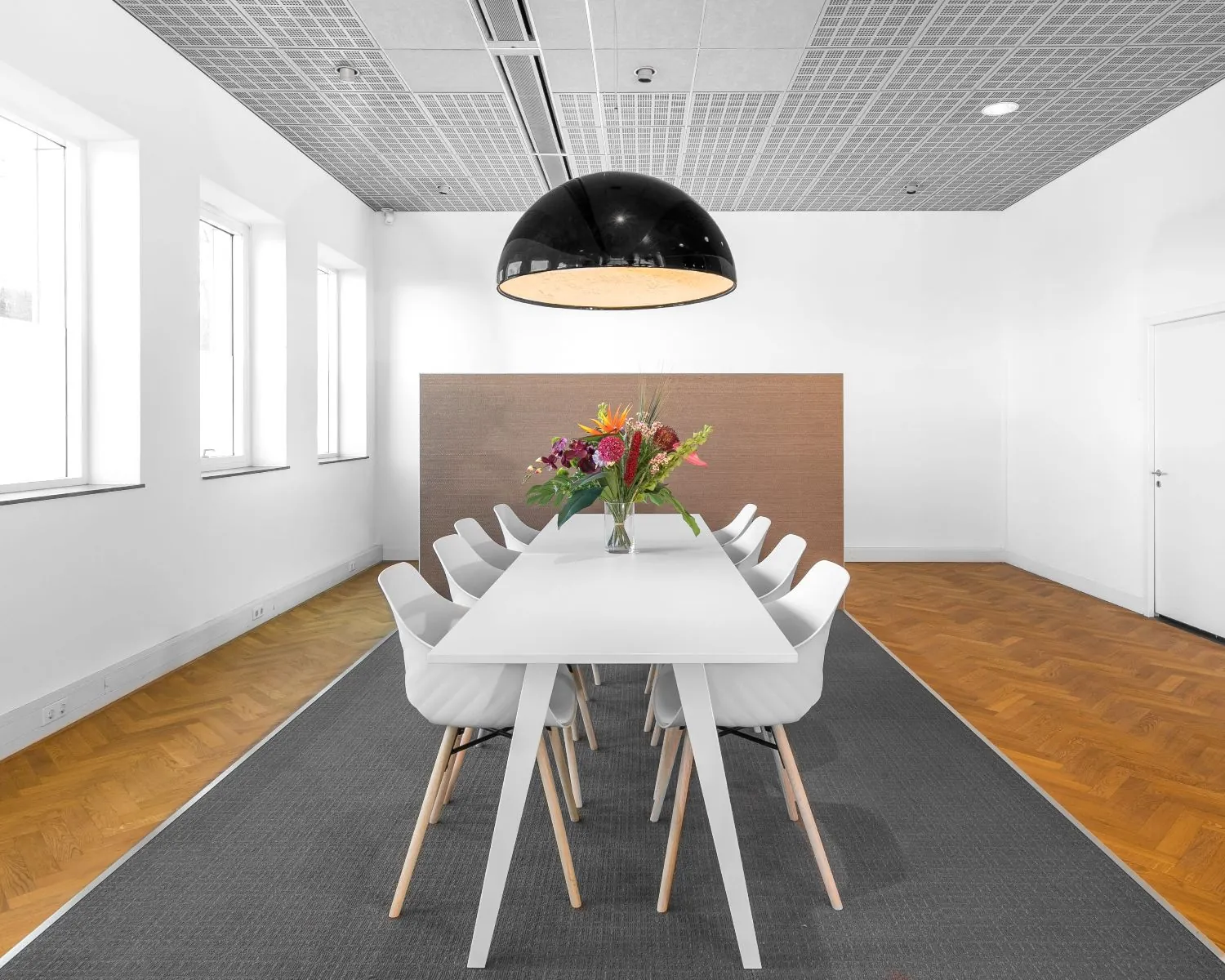 Moderne vergaderruimte in de Queenstower aan de Delflandlaan in Amsterdam met een lange witte tafel, designstoelen en een grote zwarte hanglamp.