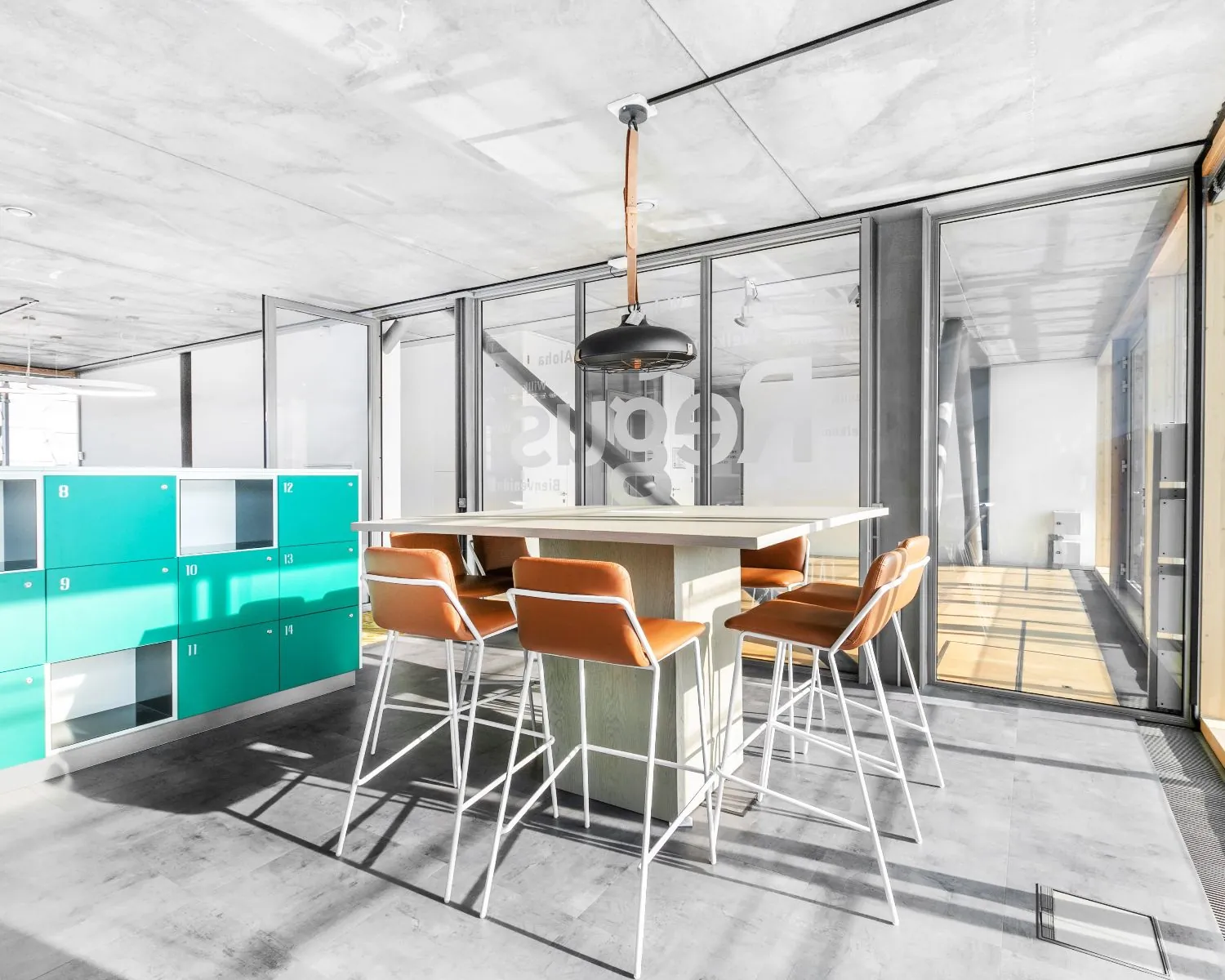 Moderne kantoorruimte in Amsterdam met hoge tafel, leren barkrukken en turquoise lockers.