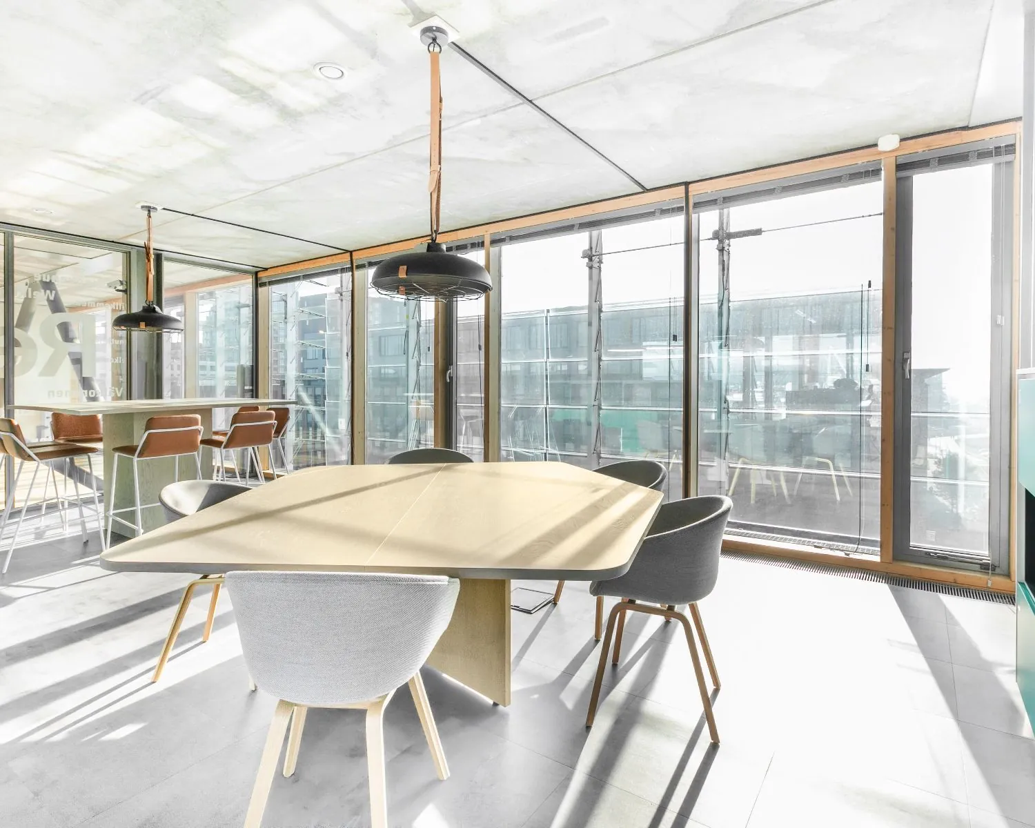 Moderne, lichte kantoorruimte te huur aan de Kraanspoor 50 in Amsterdam met grote ramen, een vergadertafel en zithoek.