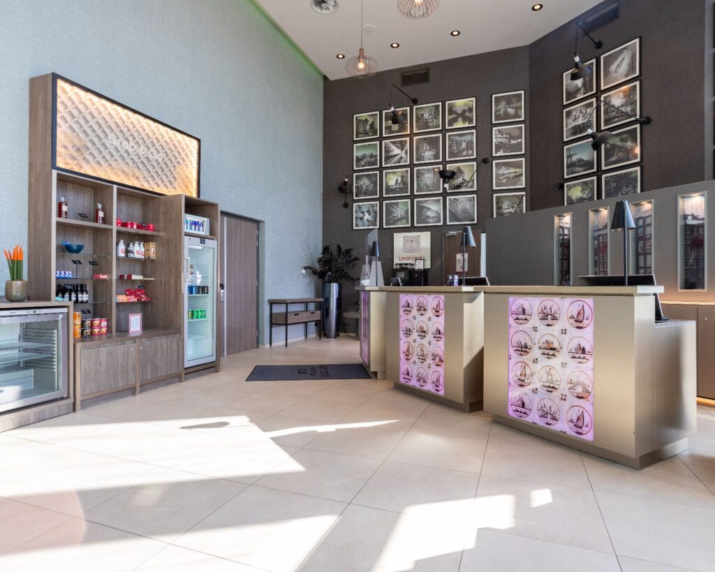 Moderne receptieruimte in het Leonardo Royal Hotel aan de Paul van Vlissingenstraat 24 in Amsterdam met displays, foto's en een minimarkt.