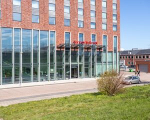 Voorgevel van het Leonardo Royal Hotel aan de Paul van Vlissingenstraat 24-8 in Amsterdam met moderne glazen entree.