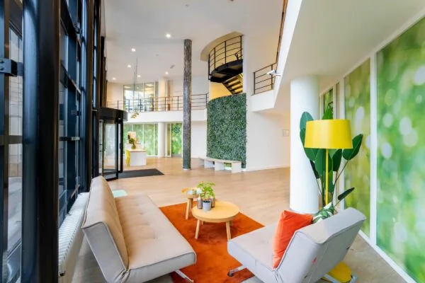 Moderne en lichte kantoorlobby aan de Overschiestraat 186 in Amsterdam met zithoek, groene wand en open trap.