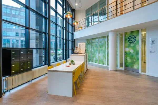 Moderne, lichte kantoorruimte met hoge ramen, kleurrijke zithoeken en de entree van Smart Office aan de Overschiestraat 186 in Amsterdam.