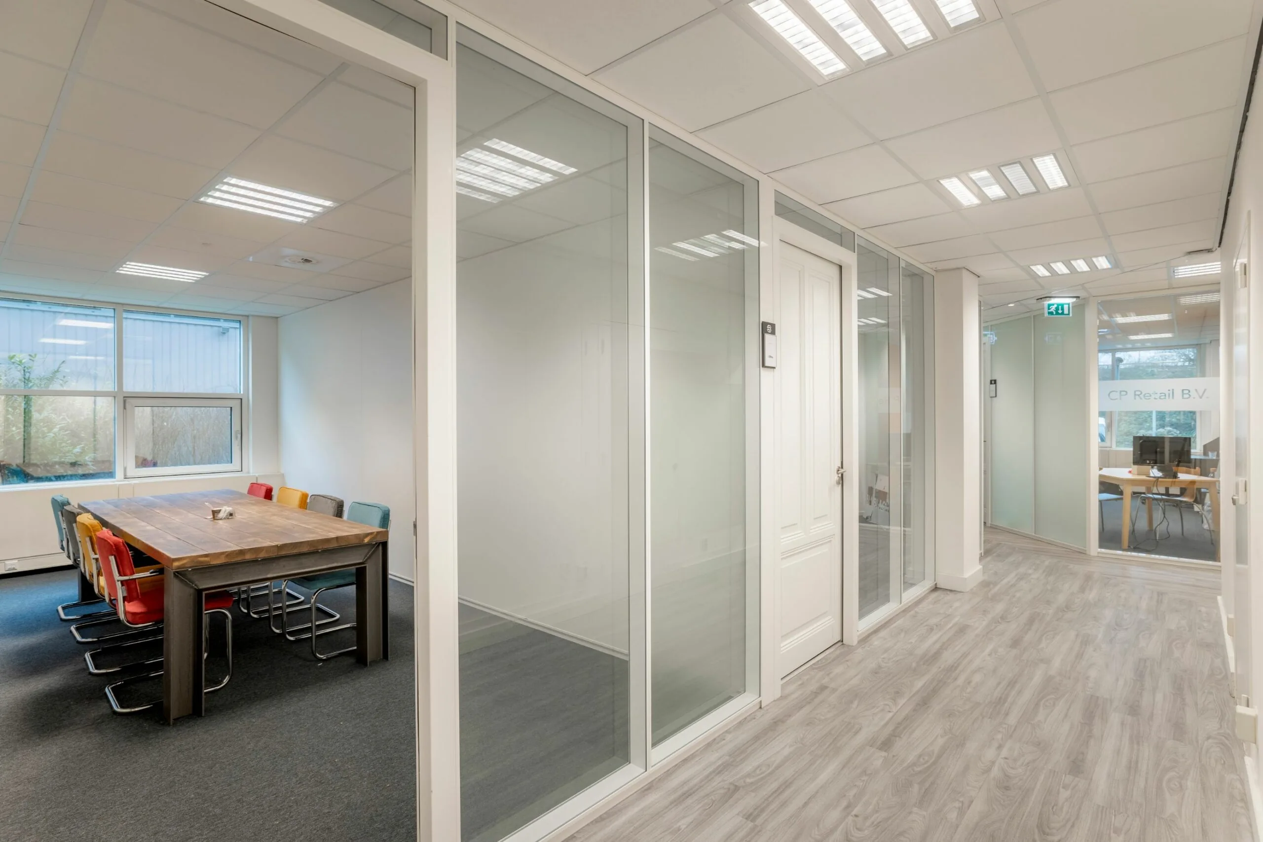 Moderne kantoorruimte aan de Overschiestraat 186 in Amsterdam met glazen wanden, vergaderruimte en houten vloer.