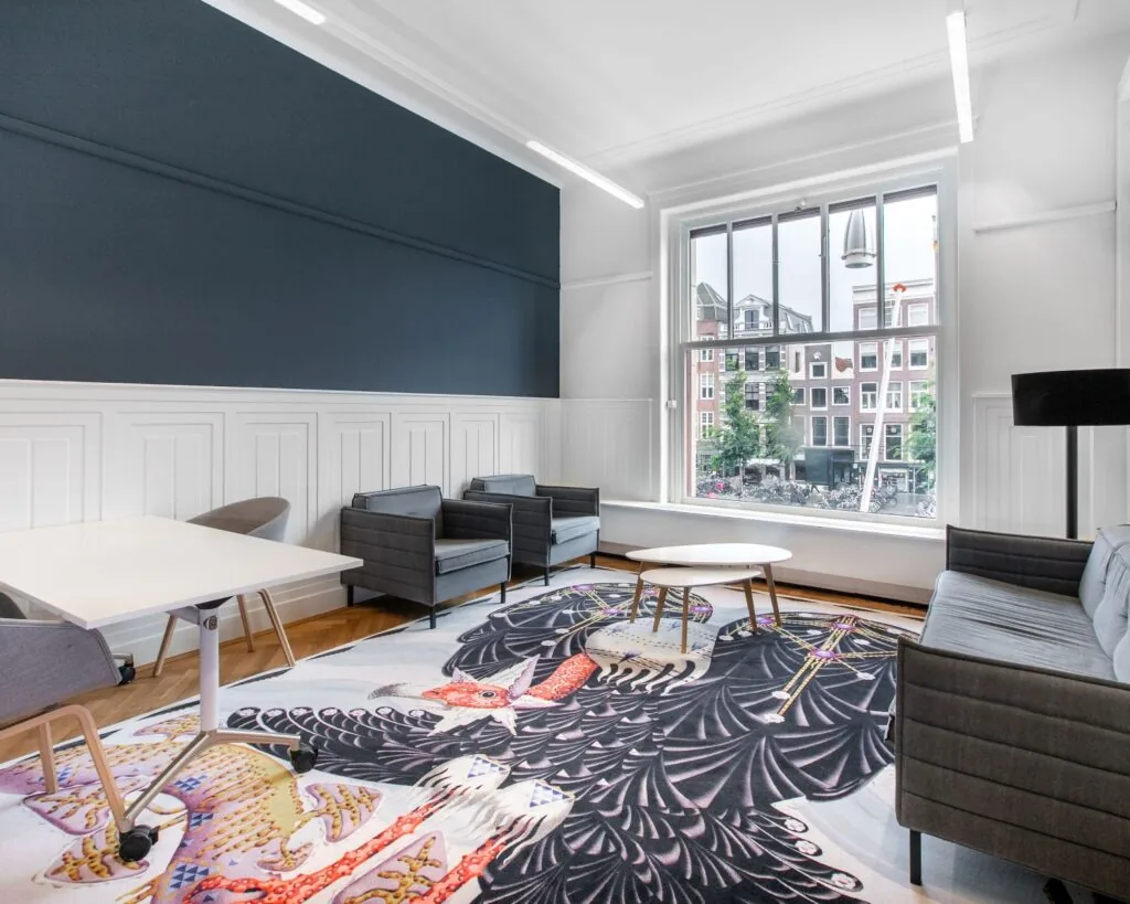 Moderne kantoorruimte aan het Rokin in Amsterdam met zithoek, grote raampartij en opvallend vloerkleed.