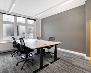 Moderne kantoorruimte met vier bureaustoelen en grote ramen aan het Rokin in Amsterdam.