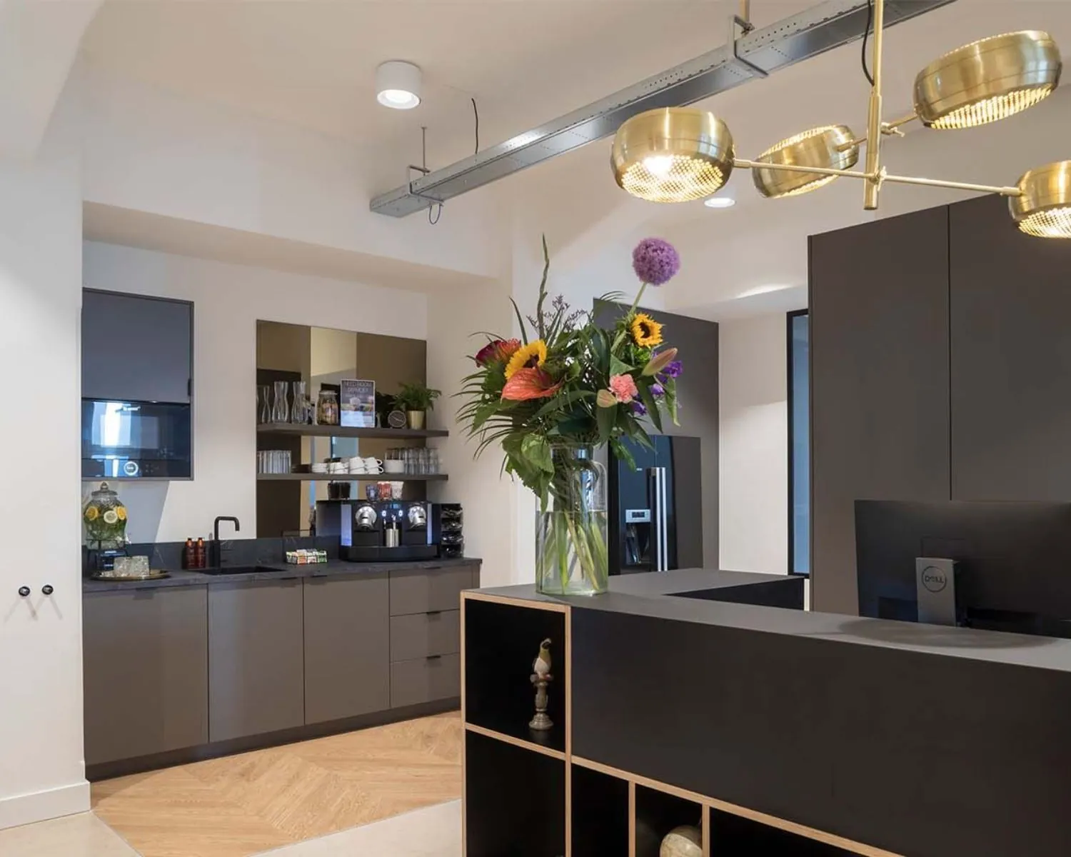 Moderne kantoorruimte aan het Rokin in Amsterdam met een kitchenette, stijlvolle receptiebalie en een opvallend bloemstuk.