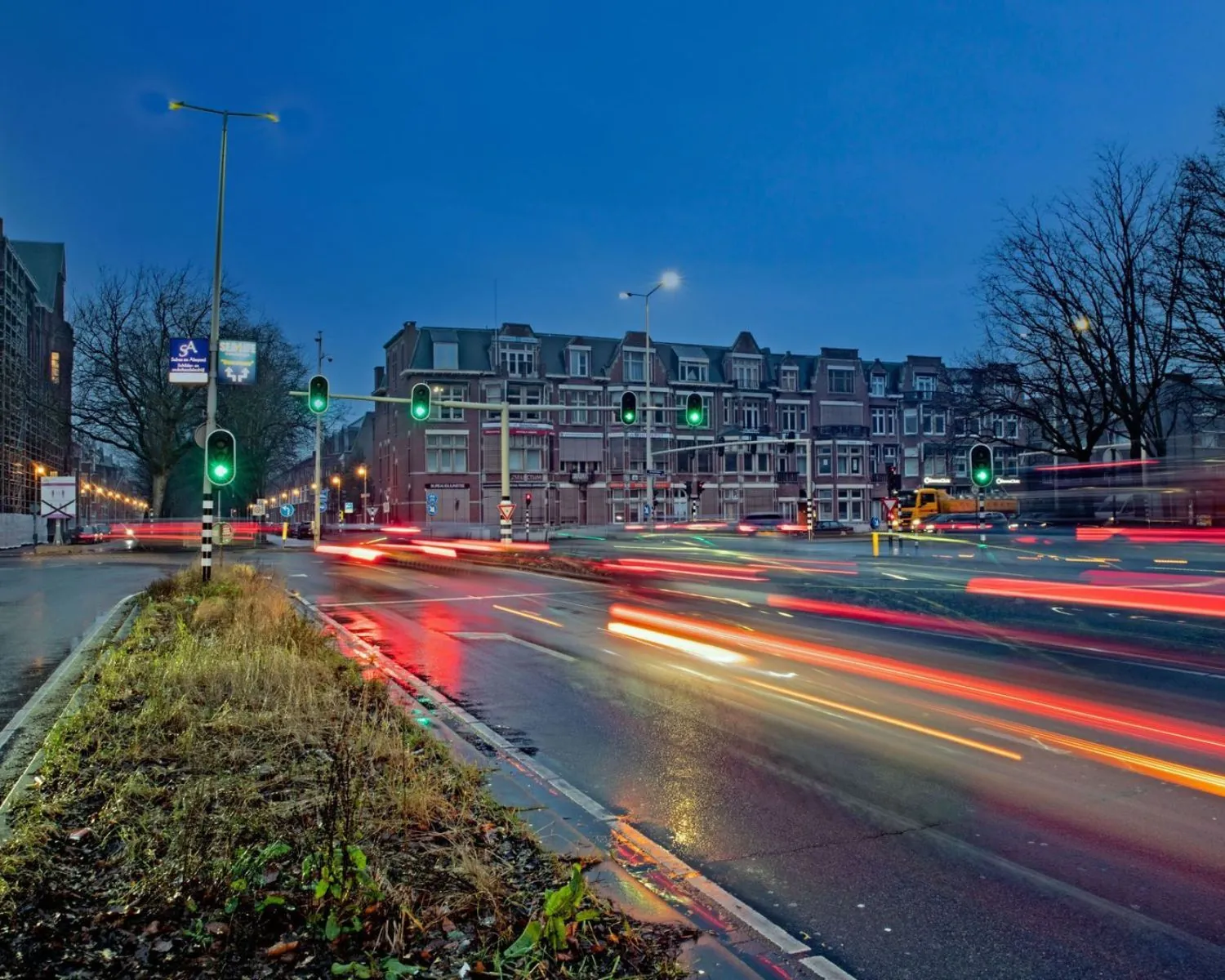 Drukke kruising bij de Benoordenhoutseweg in Den Haag met lichtsporen van voorbijrijdend verkeer in de avondschemering.