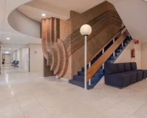 Moderne kantoorruimte aan de Benoordenhoutseweg met opvallend bakstenen muurelement en blauwe trap.