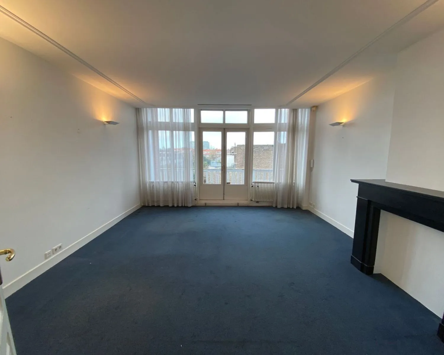 Lichte kantoorruimte met donkerblauwe vloer, open haard en grote ramen aan de Benoordenhoutseweg 21.