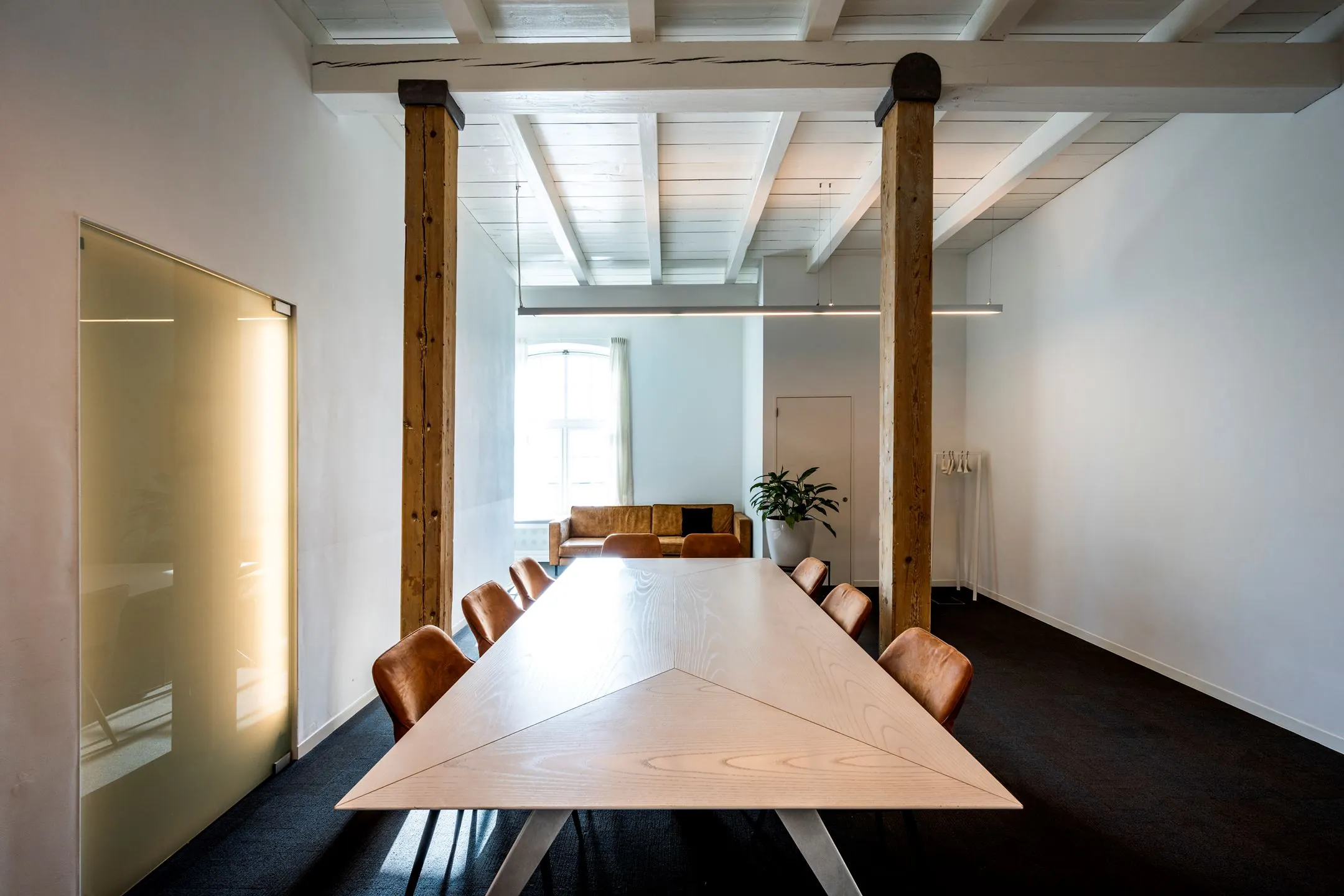 Moderne vergaderruimte met houten tafel en leren stoelen in kantoor De Bell aan de Sarphatistraat 370.